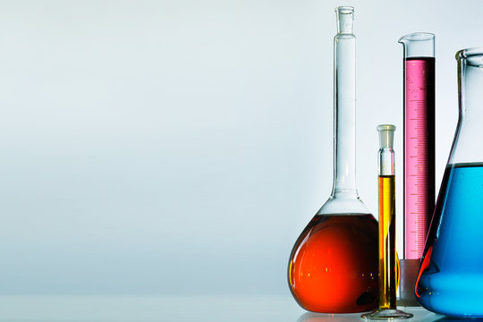 Different laboratory glassware with color liquid and with reflection