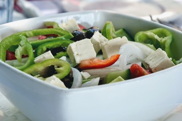 Delicious Greek salad in a bowl. Salad made of cucumber, tomato, pepper, lettuce, onion, feta cheese and olives. Concept for a tasty and healthy vegetarian meal. Healthy food. Close up