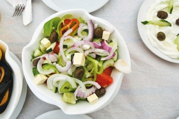 Delicious Greek salad in a bowl. Salad made of cucumber, tomato, pepper, lettuce, onion, feta cheese and olives. Concept for a tasty and healthy vegetarian meal. Healthy food. Close up. Top view