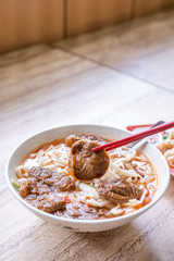 Beef noodle - Taiwan ramen meal with tomato sauce broth in bowl on bright wooden table, famous chinese style food, close up, top view, copy space