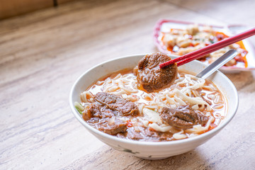 Beef noodle - Taiwan ramen meal with tomato sauce broth in bowl on bright wooden table, famous chinese style food, close up, top view, copy space