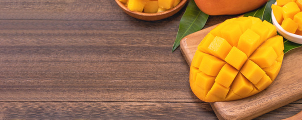 Fresh chopped mango cubes on wooden cutting board and rustic timber background. Tropical summer fruit concept, close up, macro, copy space.
