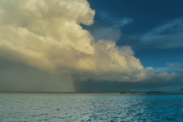 cielo celeste con gran nube blanca y arco iris