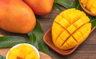 Fresh chopped mango cubes on wooden cutting board and rustic timber background. Tropical summer fruit concept, close up, macro, copy space.