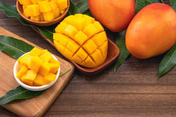 Fresh chopped mango cubes on wooden cutting board and rustic timber background. Tropical summer...