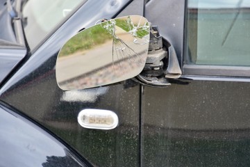 Road accident.  Black car with a broken side mirror. Crushed automobile side view mirror. Parked auto with breakdown glass. Car vandalism. 