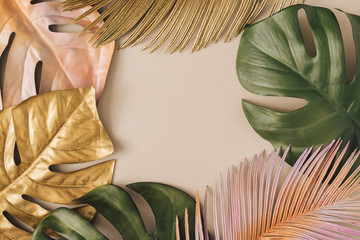 Creative layout made of colorful and golden tropical leaves and palms on beige background. Minimal...