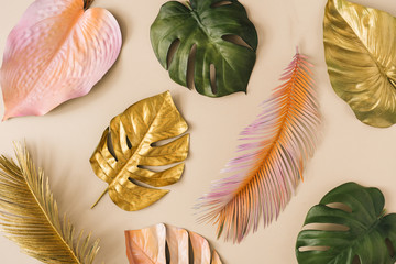 Creative layout made of colorful and golden tropical leaves and palms. Minimal summer exotic...