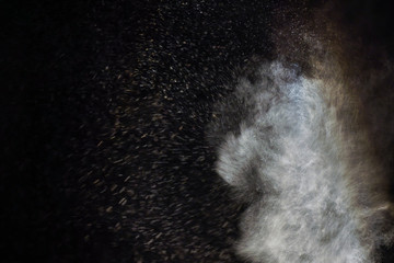 Freeze motion of white particles on black background. Powder explosion. Abstract dust overlay...