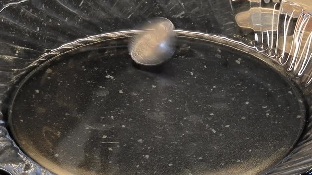 4K footage 30fps. 2 euro coin stand up and start twisted asa crazy on a glass plate. Loop 16 seconds 4K macro video with zoom-out and zoom-in effects.