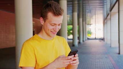 A young man using a phone outdoors.