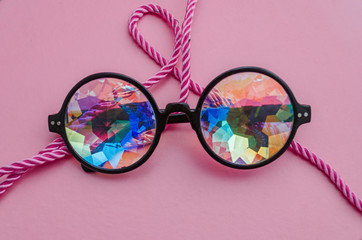 Designer glasses with kaleidoscope lenses with a rope on a pink background - obrazy, fototapety, plakaty