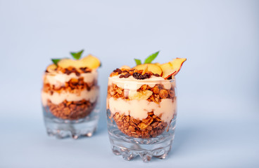 two parfaits of granola, yogurt, fresh peach, banana chips, mint, healthy breakfast