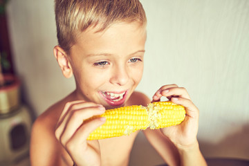 Hungry child with a corncob in his hands