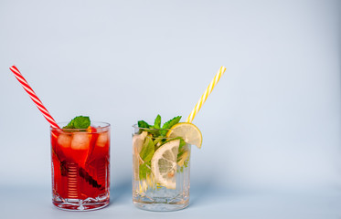 two glasses of lemonade with lime, lemon and mint leaves, peach and ice