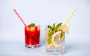 two glasses of lemonade with lime, lemon and mint leaves, peach and ice