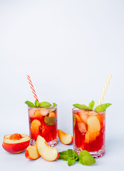 two cocktails with lemonade with peaches, mint leaves and ice