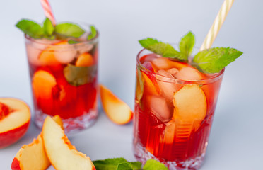 two cocktails with lemonade with peaches, mint leaves and ice