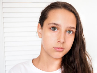 Fototapeta premium Portrait of a beautiful young caucasian tanned girl on a white background closeup. Brown long health hair. Calm face, beauty concept.