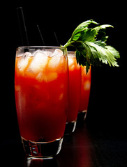 Bloody Mary cocktails with ice cubes and celery on black