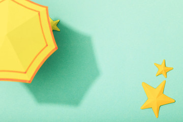 top view of paper yellow umbrella near starfishes on turquoise background