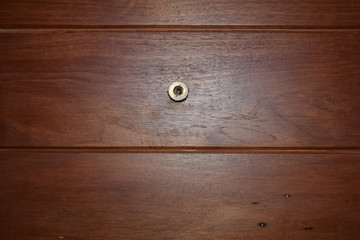golden door lens peephole with glittering on the brown wooden door