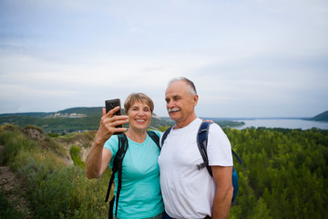 Senior couple with backpacks on the mountain taking a selfie.  Senior couple walking in nature. travel tourism concept