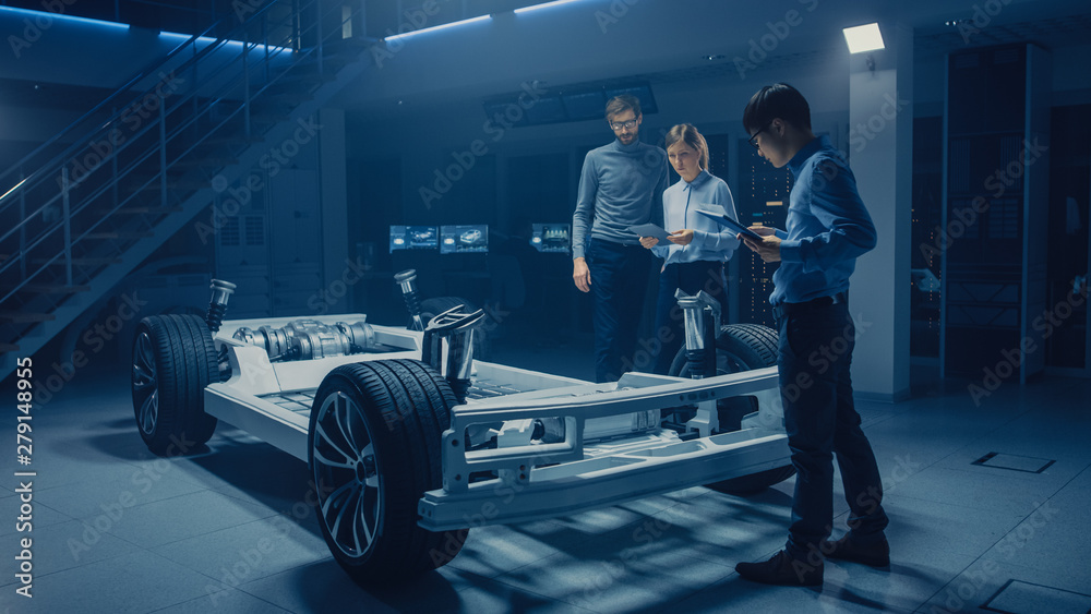 Poster diverse automobile engineers talking while working on electric car platform chassis prototype. in au