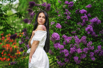 Beautiful woman enjoying lilac garden, young woman with flowers in green park.