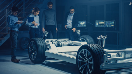 Team of Automotive Engineers Designing Electric Car Platform Chassis Prototype, Taking Measures,...