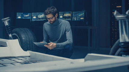 Automobile Design Engineer Sitting Beside Hybrid Electric Car Chassis Platform Prototype, Using...