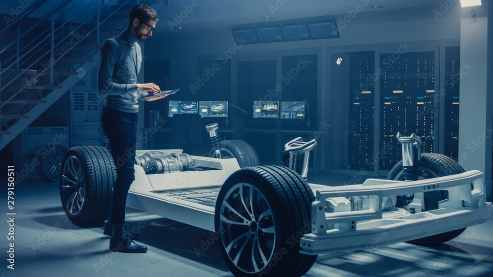 Poster automobile engineer working on electric car platform chassis prototype, using tablet computer with 3