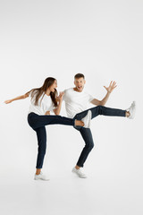 Fototapeta na wymiar Beautiful young couple's portrait isolated on white studio background. Facial expression, human emotions, advertising concept. Copyspace. Woman and man jumping, dancing or running together.