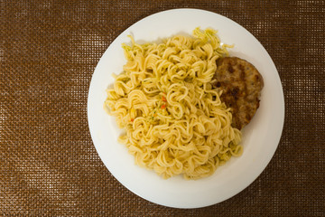 Meat roast cutlet with boiled pasta, spaghetti on a brown background. Simple fast food.