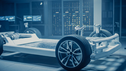 Automobile Engineers Discussing and Designing Electric Car Chassis Platform Using Tablet Computers...