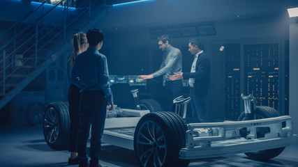 Team of Automobile Design Engineers in Automotive Innovation Facility Working on Electric Car Platform Chassis Prototype that Includes Wheels, Suspension, Hybrid Engine and Battery