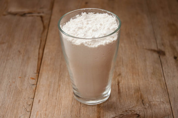 Flour in glass bowl on rustic wooden table closeup