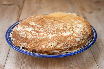Stack of pancakes on blue plate on rustic wooden background