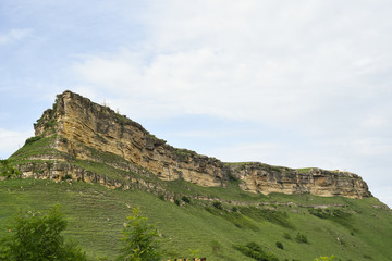 Nature, background. Rural coastal hills, mountains, blue sky, white clouds, green meadows, green grass, fields.