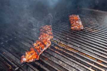 outdoor backyard thin strip beef stake on a propane gas grill with smoke