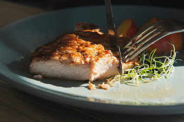 Knife and fork cuts grilled steak on turquoise plate. Juicy turkey white meat closeup. Chicken fillet. 