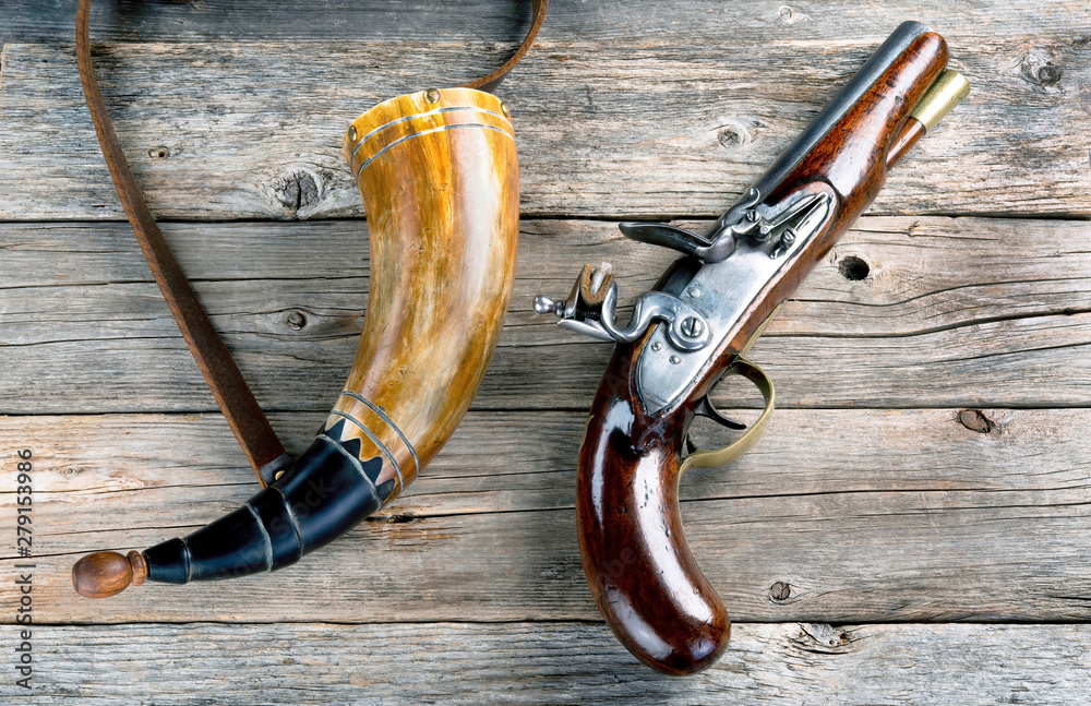 Wall mural antique flintlock pistol and gunpowder horn.