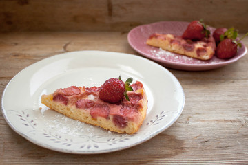 Piece of round strawberry berries tart pie pudding on white and pink plates on rustic wooden background
