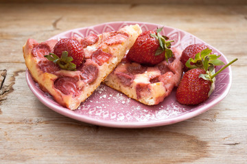 Piece of round strawberry berries tart pie pudding on pink plate on rustic wooden background