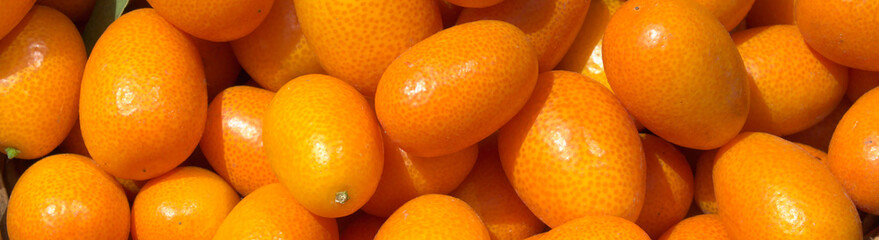 Fresh juicy kumquats in a basket in the market. Orange background of fresh oranges. Closeup