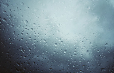 A windshield filled with rain drops in an overcast sky.