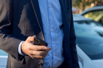 Close up of a man in business suit using mobile smart phone