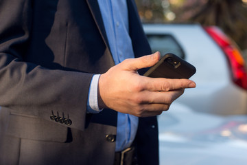 Close up of a man in business suit using mobile smart phone