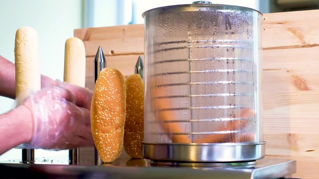 Hotdog machine, cook puts warming buns on