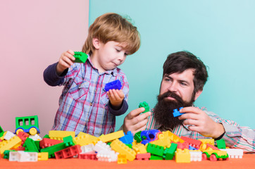 Naklejka premium Enjoying time in play club. love. child development. father and son play game. happy family leisure. small boy with dad playing together. building with colorful constructor. I am busy